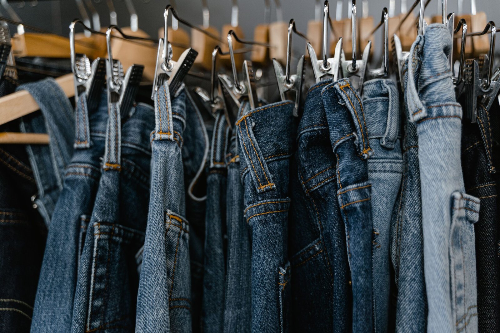 1. A collection of blue denim jeans hanging on clothing racks, showcasing different washes, textures, and contrasting stitching.